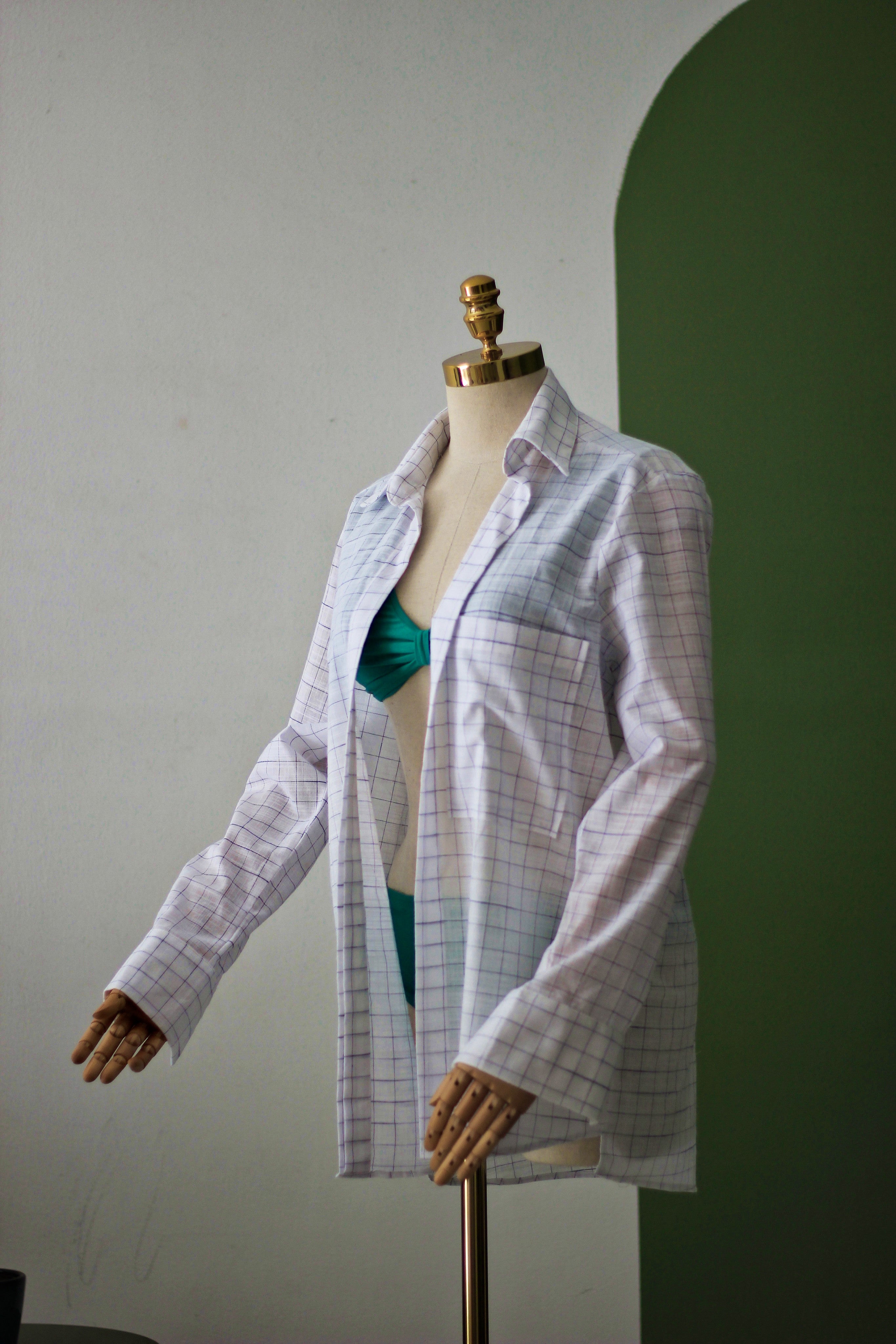 Mannequin wearing a checkered shirt over a green top against a plain background