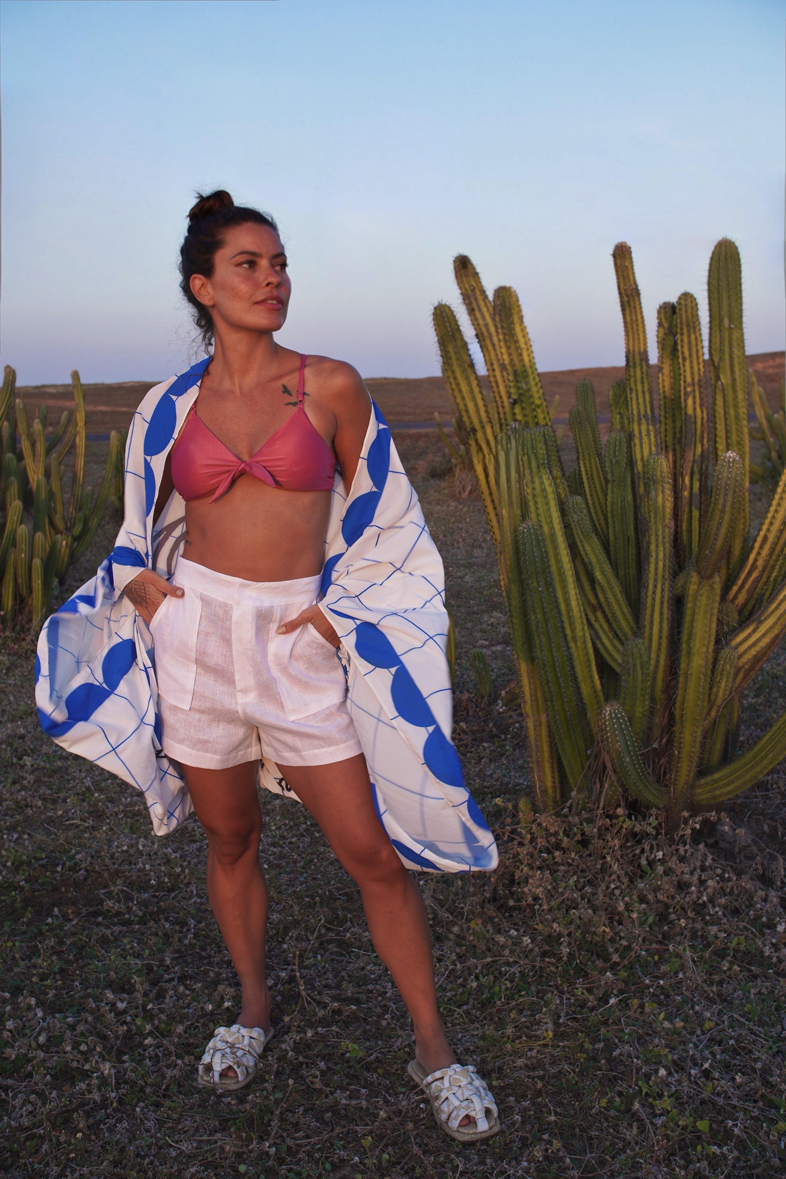 Woman in a pink bikini top and white shorts with a blue and white patterned cover-up standing in front of cacti.
Resort-ready high-rise tailored shorts with patch front pockets, high-rise fit — crafted for elevated summer style, tropical ease, and timeless versatility