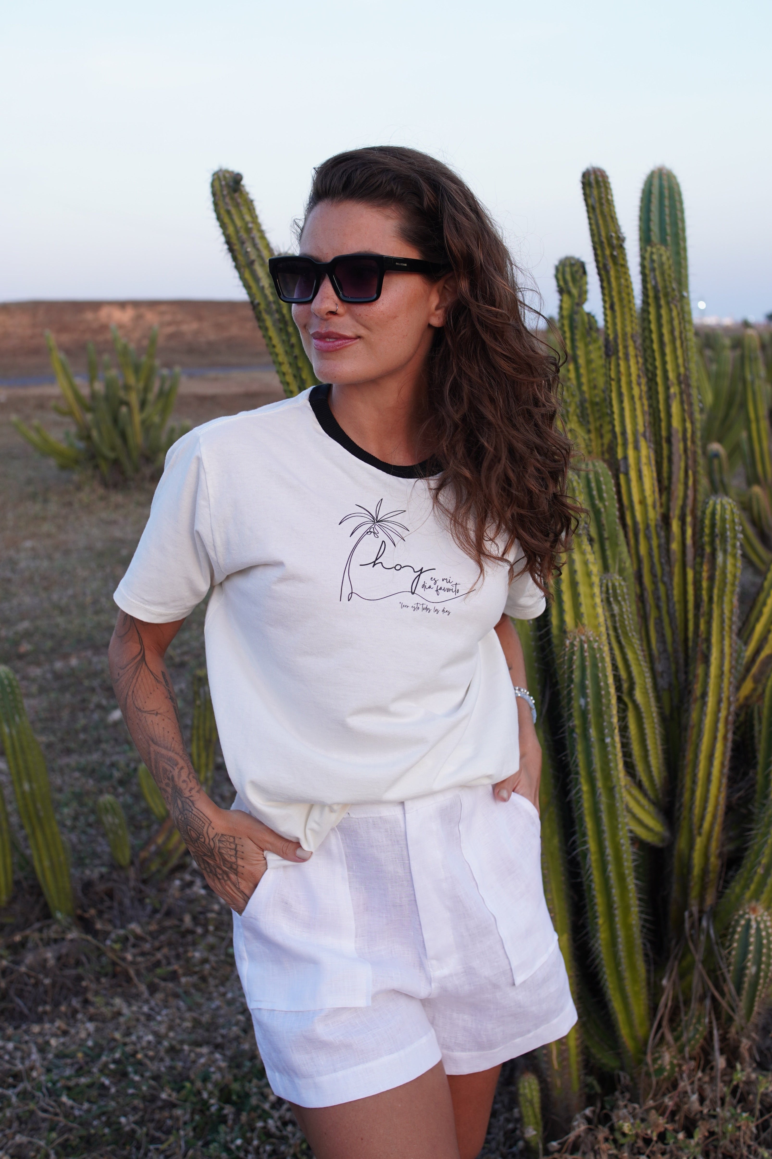 Woman in a white fresh and elegant tailored linen shorts and a cotton t-shirt standing in front of cacti
white viscose resort shorts minimalist summer essentials, premium resort wear vacation-ready style