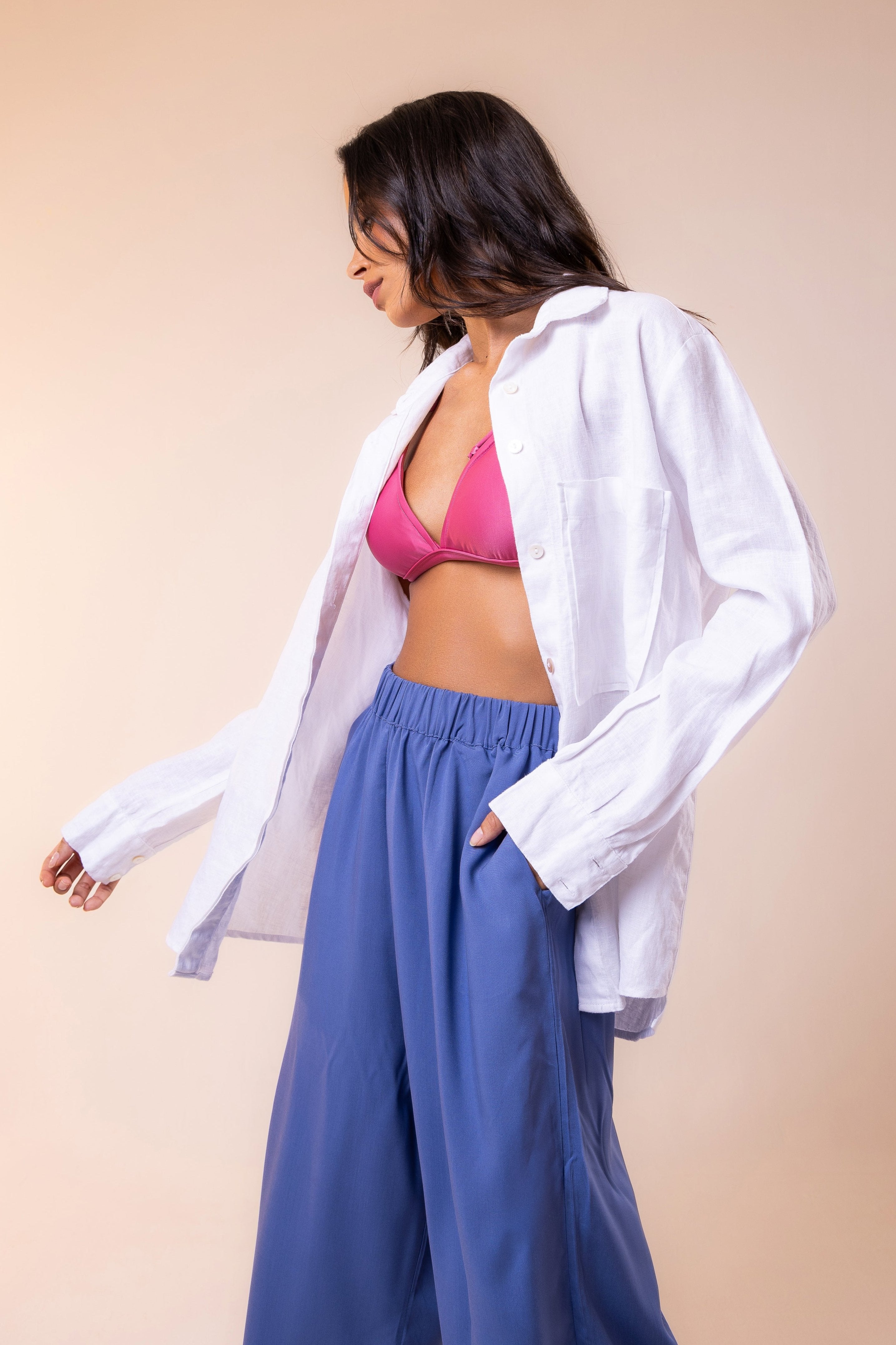 Hoy Swim look featuring a white linen shirt with a front pocket, triangle top pink bikini, and blue flowy and frash viscose pants — a blend of comfort, elegance, and the free spirit of tropical summer. Perfect for resort days or effortless beachside style