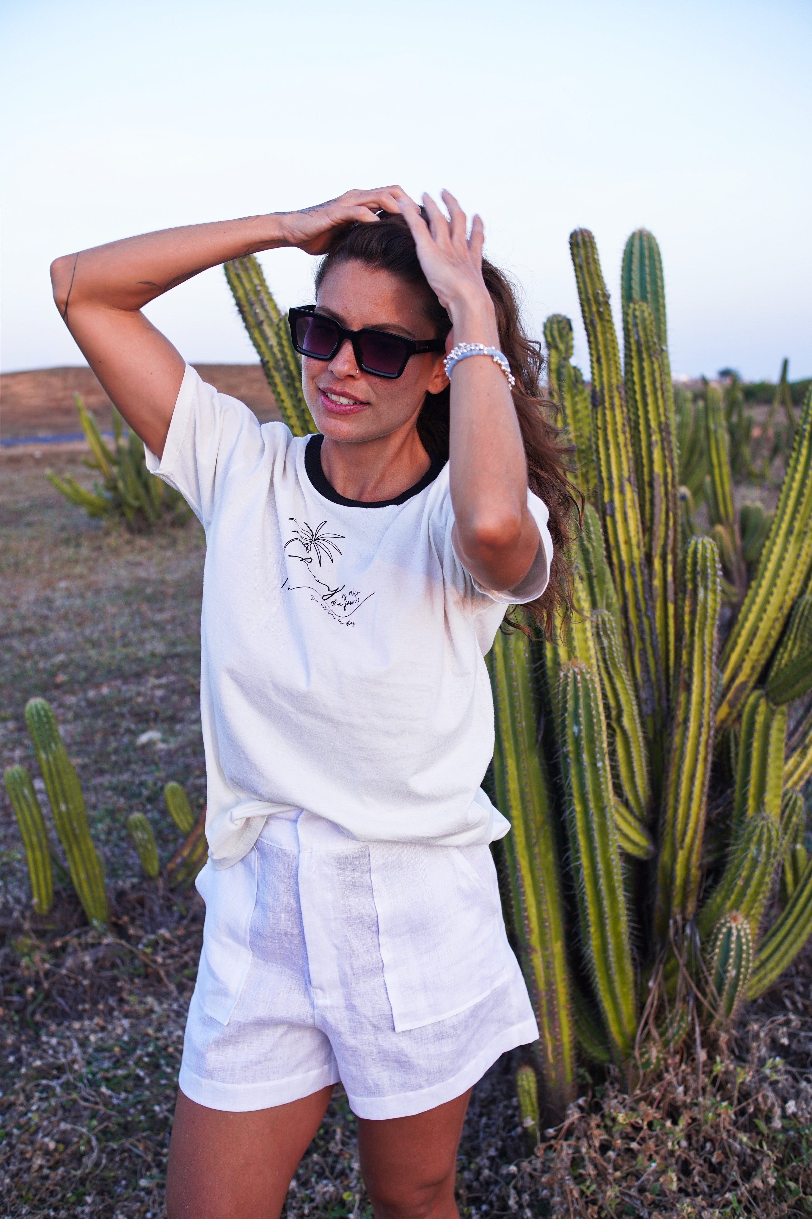 Woman in white linen outfit with sunglasses standing in front of cacti
White linen tailored resort shorts with clean pleats and a high-rise silhouette — a minimalist summer staple designed for elevated casual elegance.