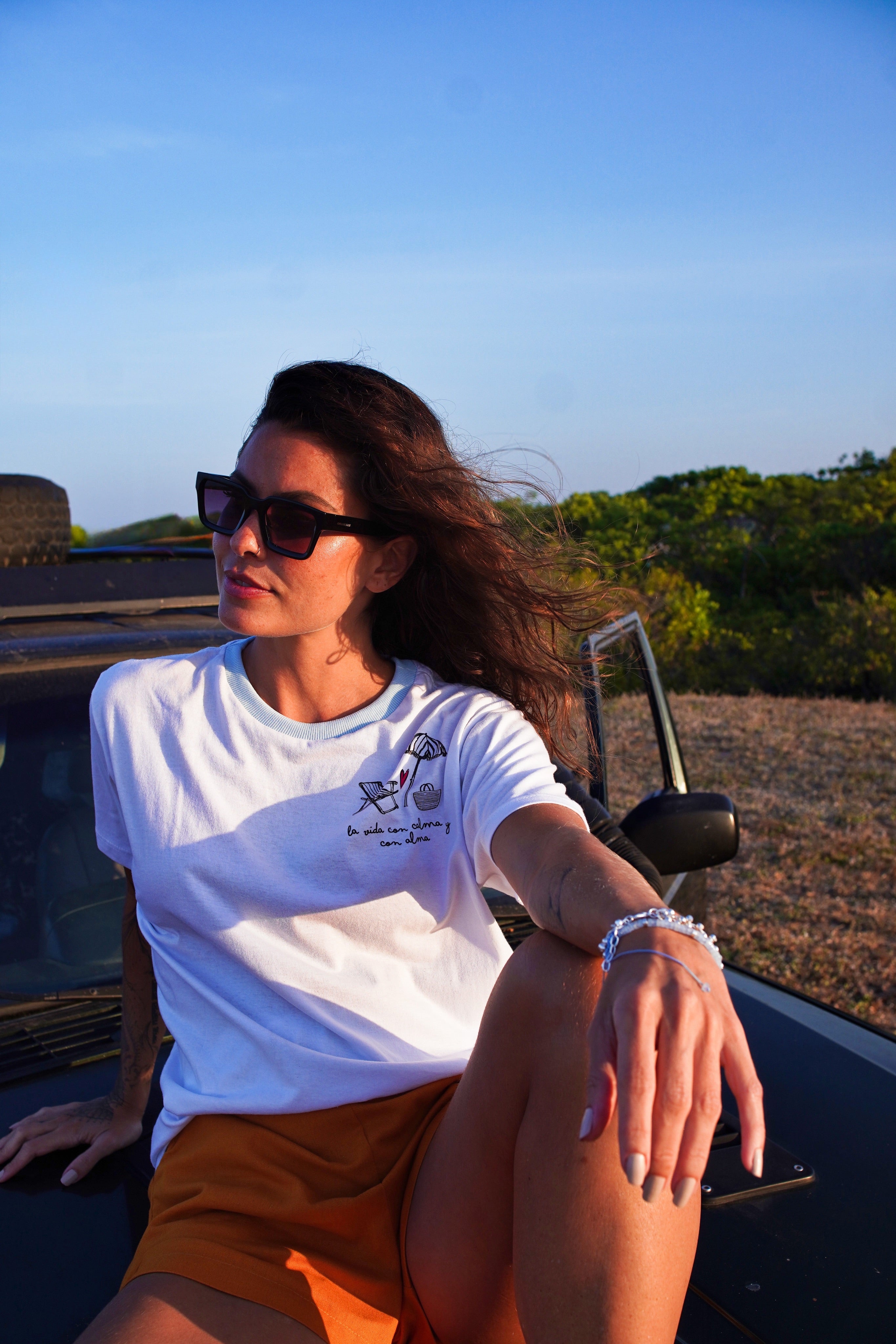 Woman sitting in an open car with a scenic background.
A lightweight white graphic T-shirt tropical lifestyle fashion
