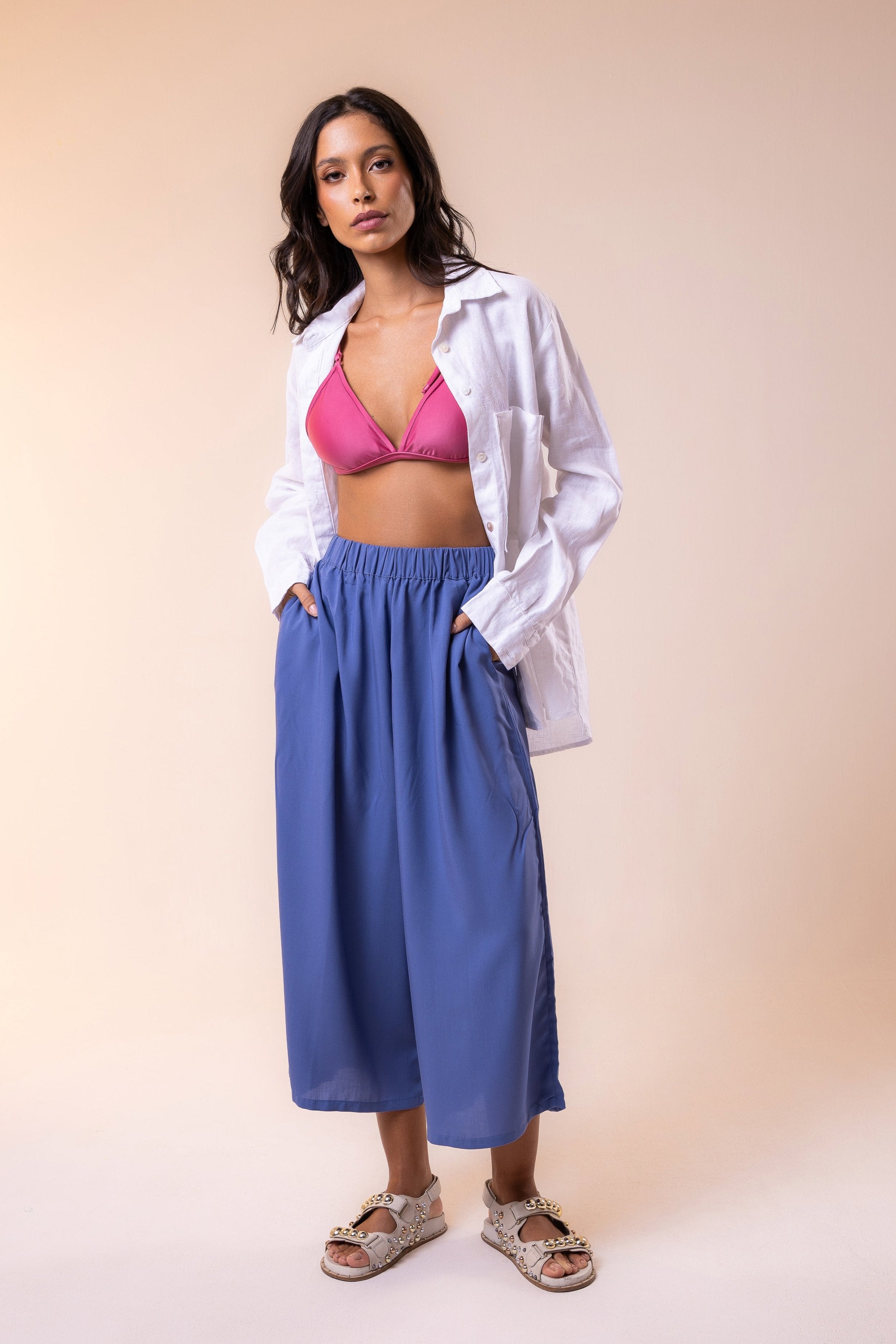 Hoy Swim look featuring a white pure linen shirt, triangle top pink bikini, and blue flowy viscose pants with pockets— a blend of comfort, elegance, and the free spirit of tropical summer. Perfect for resort days or effortless beachside style.